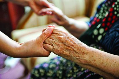 Care aide holding hands of elderly resident
